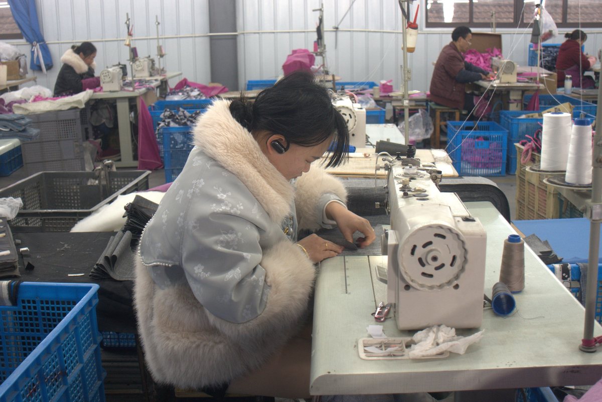 A seamstress sewing doll-pram fabric in the Apexcel workshop