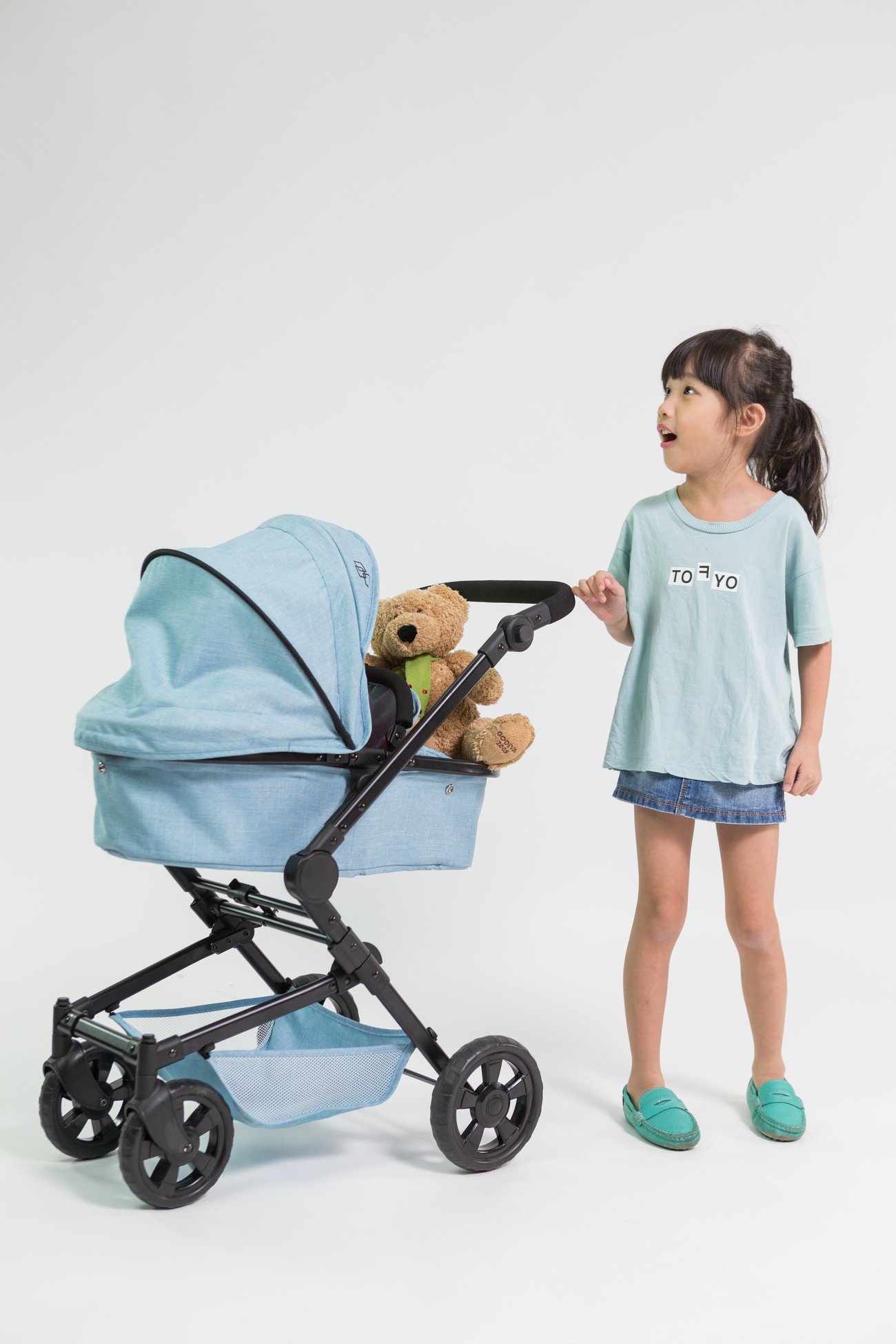A child beside a Triokid doll pram in the studio