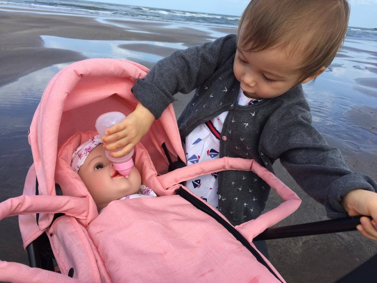 A toddler playing with a Triokid pram at the beach